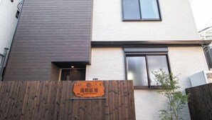 A modern building with a wooden fence, a sign with Japanese characters, and a small tree.