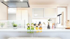 A modern kitchen with a white countertop, a stainless steel range hood, and decorative figurines.