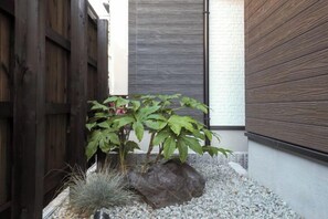 A small garden with a plant, rocks, and a wooden fence. - youmeiyado asahi　take 2F (Osaka)