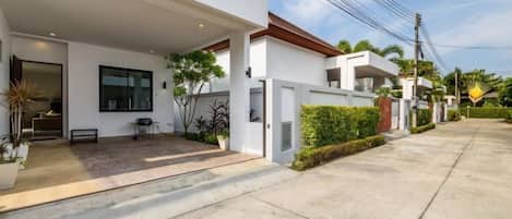 A modern two-story house with a covered patio, a garage, and a well-maintained garden.