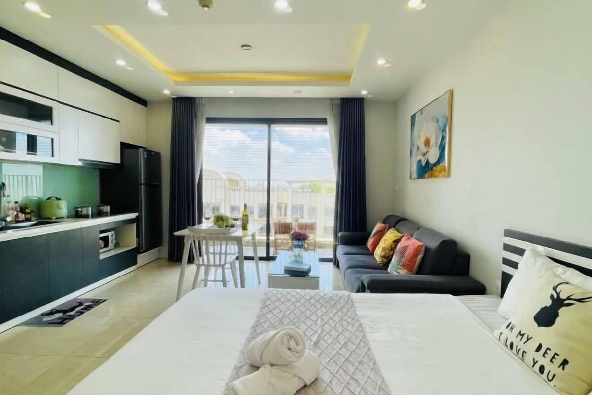 Ein modernes Hotelzimmer mit Bett, Sofa, Essbereich und Küche.