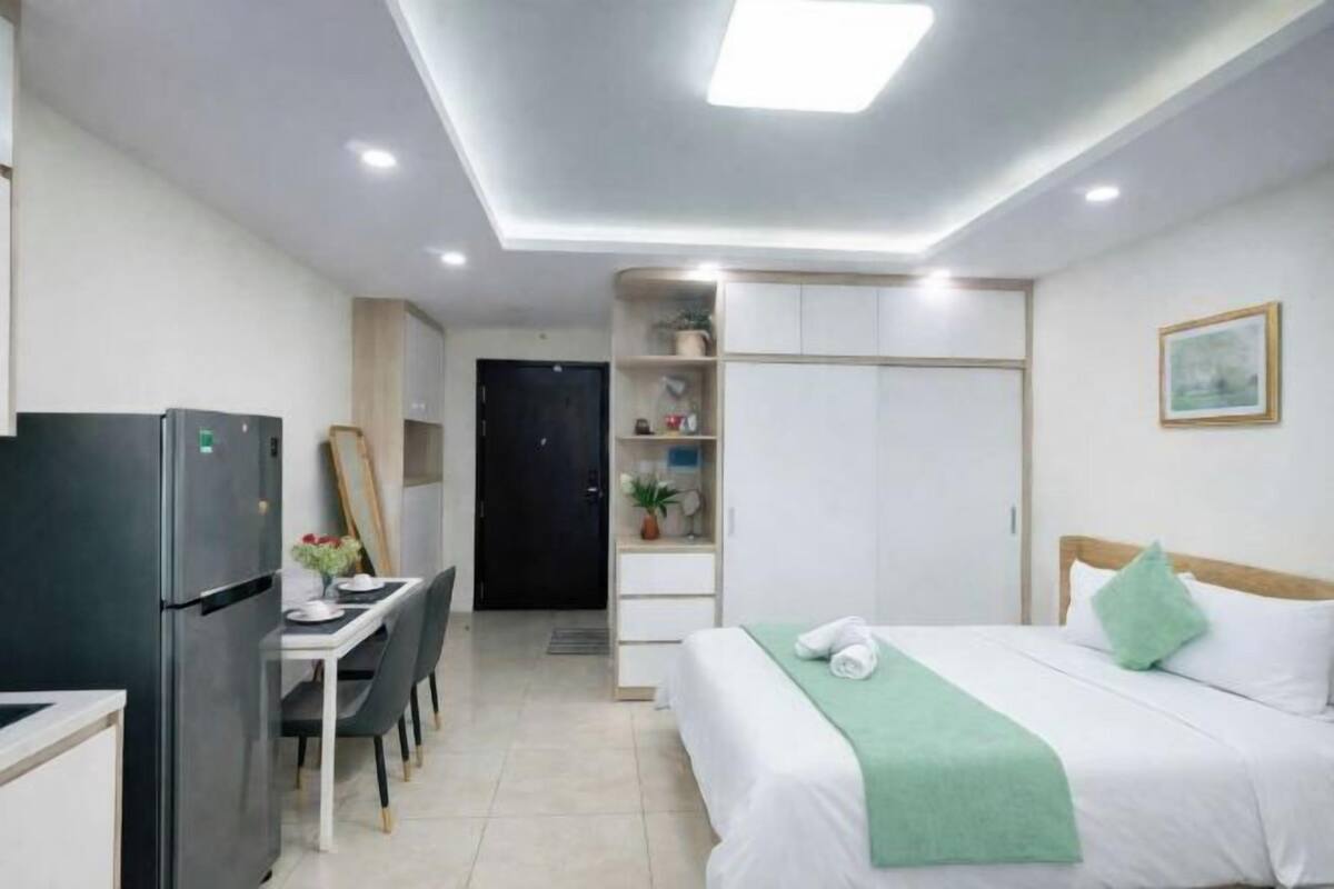 Ein Hotelzimmer mit einem Bett, einem Schreibtisch mit Stühlen, einem Kühlschrank und einem Kleiderschrank.