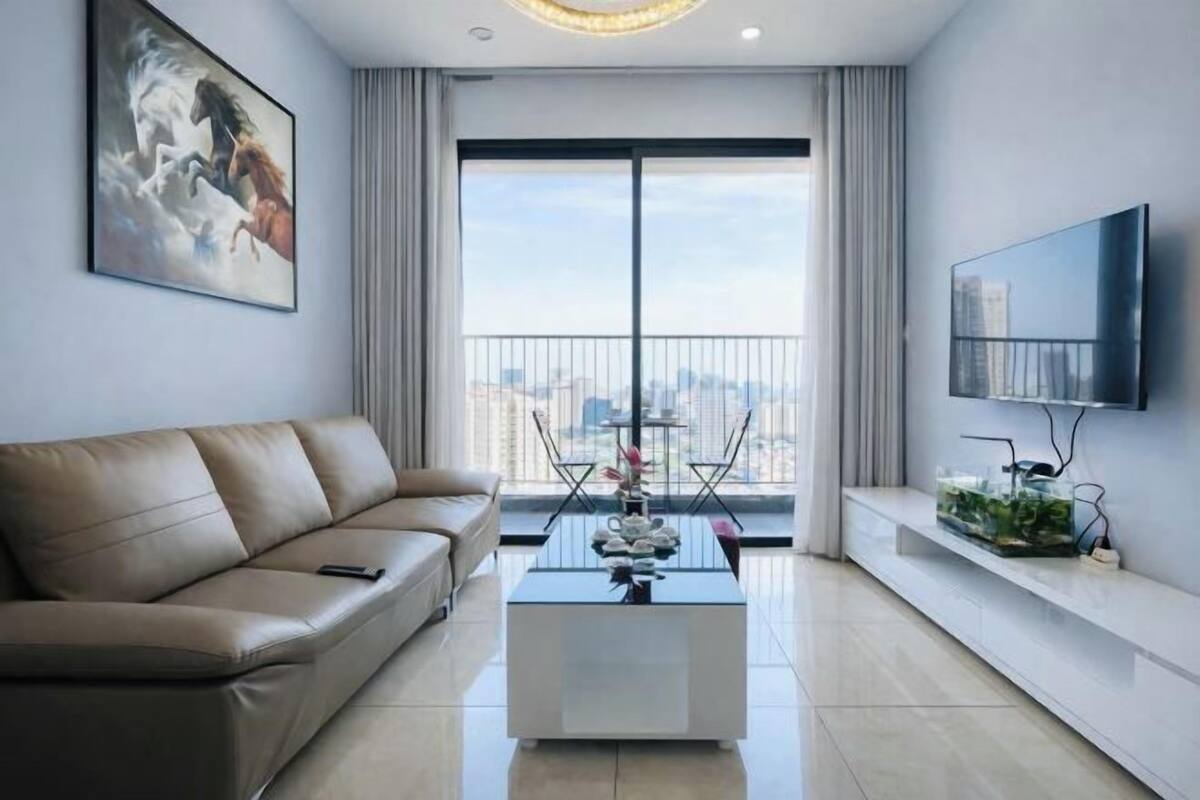 Ein modernes Wohnzimmer mit einer Couch, einem Couchtisch, einem Fernseher und einem Balkon mit Blick auf die Stadt.