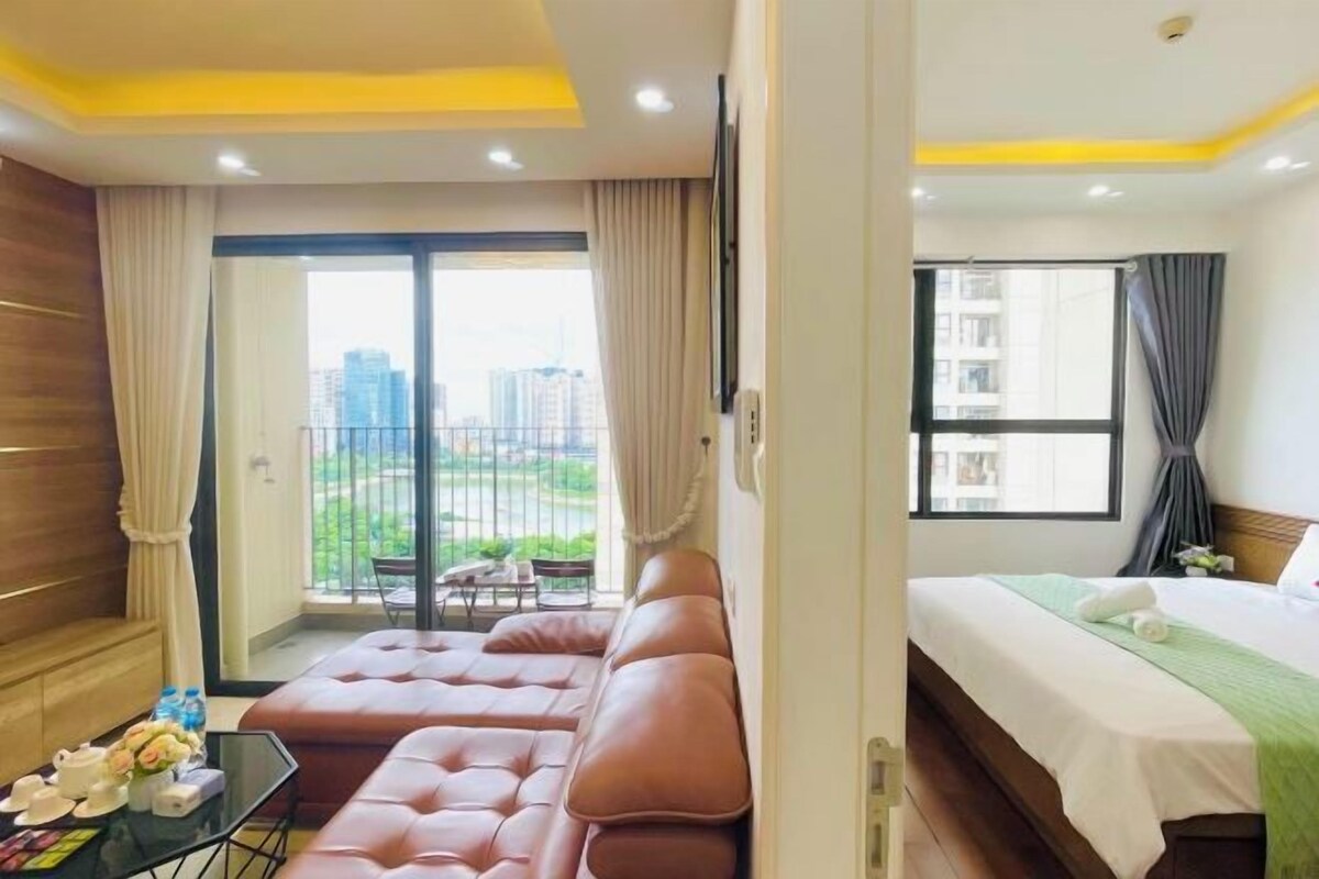 Ein Hotelzimmer mit Balkon, einer Couch, einem Bett und einem kleinen Tisch mit Blumen.