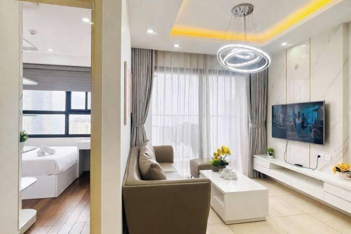 Ein modernes Wohnzimmer mit Sofa, Couchtisch, Fernseher und einem Essbereich mit einer Bank und Tisch.