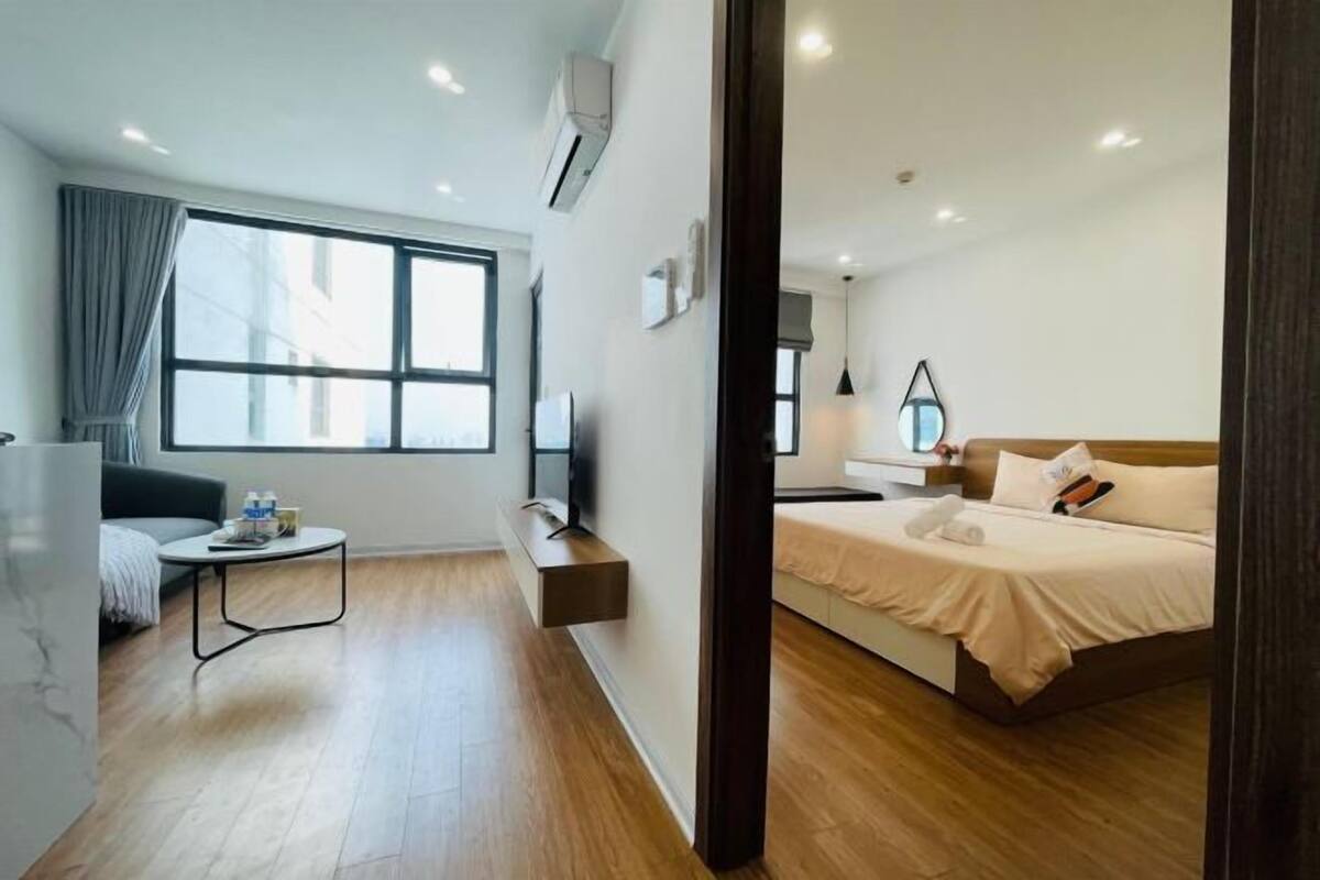 Ein modernes Hotelzimmer mit Bett, Nachttisch und einer kleinen Sitzecke mit Tisch und Stühlen.