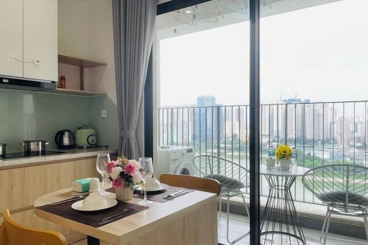 Ein Essbereich mit Tisch für zwei Personen, eine Küche mit Geräte und ein Balkon mit Blick auf die Stadt.