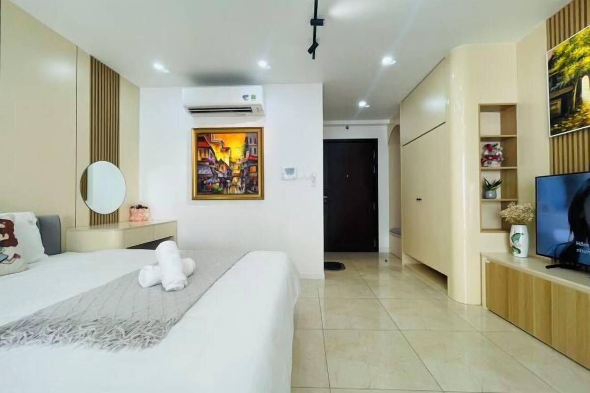 Ein modernes Hotelzimmer mit einem großen Bett, einem Flachbildfernseher, einem Bild an der Wand und einem Kleiderschrank.