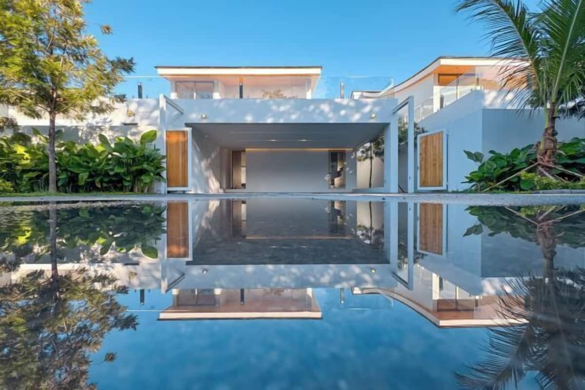 A modern house with a pool, surrounded by greenery.