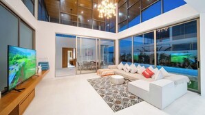 A modern living room with a large TV, a sofa set, and a chandelier. - Trinity Villa 5 Bedroom & 20 Meter Pool Luxury Villa near Bangtao Beach (Phuket)