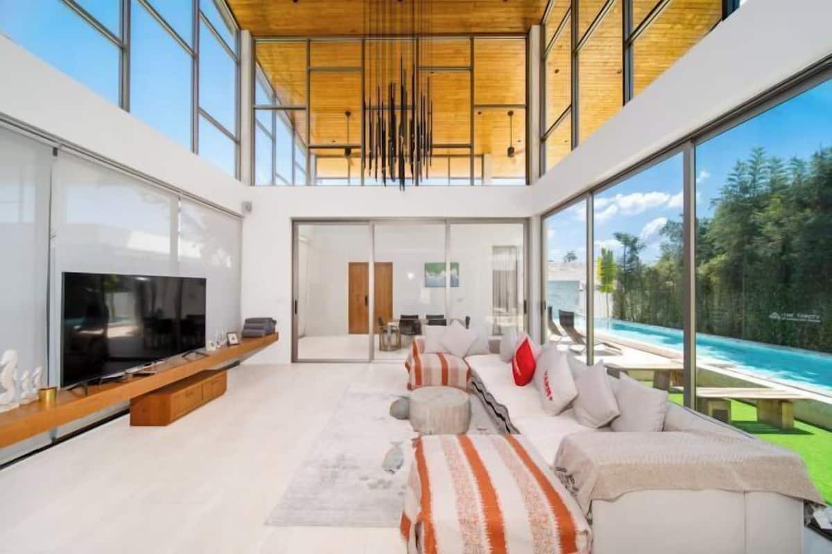 A modern living room with a large TV, a sofa, and a view of a pool.