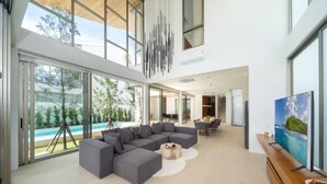 A spacious living area with a large sectional sofa, a coffee table, and a flat-screen TV. - Trinity Villa 5 Bedroom & 20 Meter Pool Luxury Villa near Bangtao Beach (Phuket)