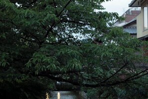 Un bâtiment traditionnel, avec un cours d’eau devant, entouré d’une végétation luxuriante.