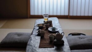 A traditional Japanese-style room with tatami mats, a low table with tea set, and shoji screens in the background. - Yasen (Kyoto)