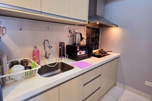 Una cocina moderna con un lavamanos de acero inoxidable, una cafetera y un escurreplatos.
