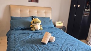 Una cama con un edredón azul, un peluche y un letrero que dice 'UNITED HOME'.