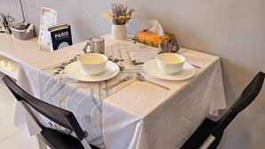 Mesa para dos personas con platos blancos, cubiertos y un cartel con el menú.