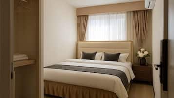 Una habitación de hotel con una cama, una mesita de noche y un armario.