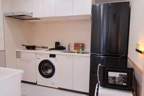 A compact kitchen with a washing machine, a refrigerator, and a small sink. - sakuranoyado (Tokyo)