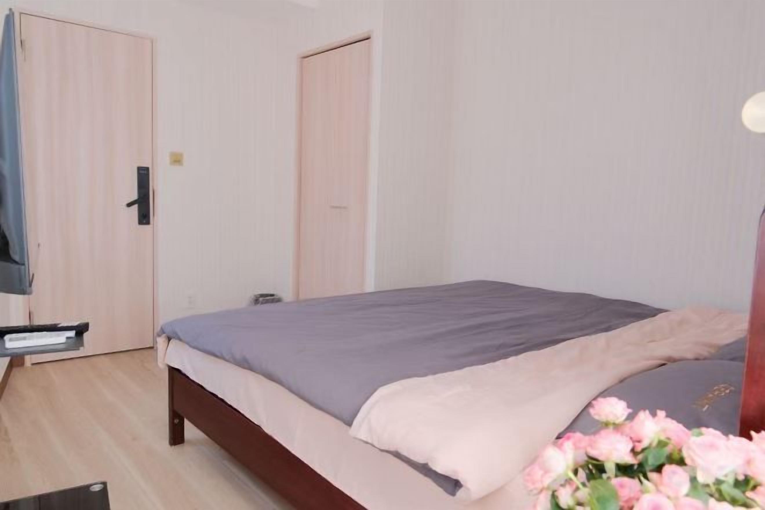 Una camera da letto con un letto, un comodino, una cassettiera e una porta.