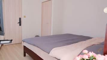 A bedroom with a bed, a nightstand, a dresser, and a door.