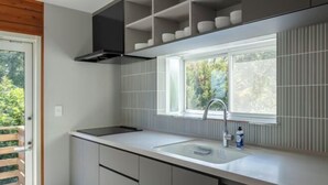 Une cuisine moderne avec une fenêtre, un évier et une étagère intégrée au-dessus du plan de travail.