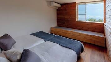 A bedroom with a bed, pillows, a bench, and a window.