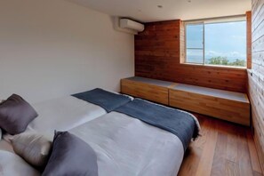 A bedroom with a bed, pillows, a bench, and a window. - VILLA ORB (Ito)