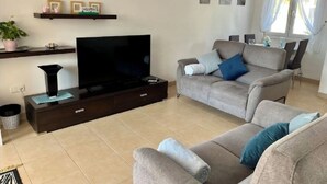 A living room with a flat-screen TV, a sofa, a coffee table, and a TV stand. - Villa Dionysus- 2 Bedroom, 2 Bathroom Villa, south facing with private pool (Torre-Pacheco)