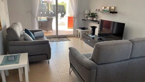 A modern living room with a grey sofa, a TV, and a small table. - Villa Dionysus- 2 Bedroom, 2 Bathroom Villa, south facing with private pool (Torre-Pacheco)