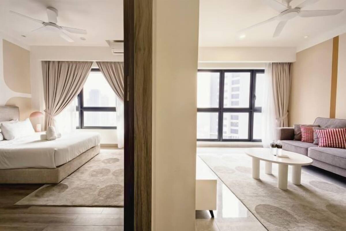 Une chambre d’hôtel moderne équipée d’un lit, d’un canapé, d’une table basse et d’une grande fenêtre.