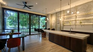 Een moderne keuken met een centraal eiland, grote ramen en een eetgedeelte met stoelen.