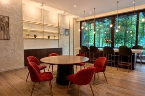 Een moderne vergaderruimte met een ronde tafel, rode stoelen en een groot raam met uitzicht op groen.
