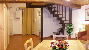 A dining area with a wooden table, chairs, and a staircase leading to an upper level. - Apartment 16 for 4 Guests (Castel del Piano)