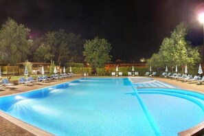 A swimming pool with lounge chairs and umbrellas, surrounded by trees and a building in the background. - Apartment 25 with 1 Bedroom - Ideal for Families (Castel del Piano)