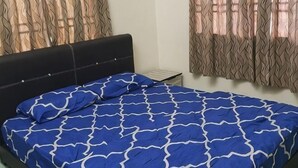 A bedroom with a bed, curtains, and a nightstand. - Homestay Che Wan (Kuala Kuantan)
