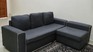 A dark-colored sectional sofa with a patterned rug in front. - Homestay Che Wan (Kuala Kuantan)