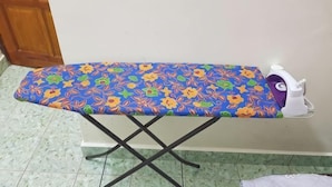 An ironing board with a floral pattern, a white iron, and a purple iron box. - Homestay Che Wan (Kuala Kuantan)