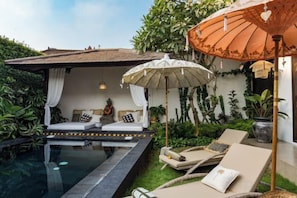 A poolside area with lounge chairs, an umbrella, and a seating area with cushions and a statue. - Jami 4BR PoolVilla, a Serenity Steps from theBeach (Bali)