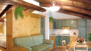 A cozy kitchen with wooden cabinets, a built-in bench, and a dining area with chairs. - Apartment 26 with 1 Bedroom and Bathroom - Simple and Comfortable (Castel del Piano)
