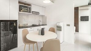 A modern kitchen with white cabinets, a marble countertop, a dining table with chairs, and a water dispenser. - Villa De Luca By Aishwarya Bali International (Bali)