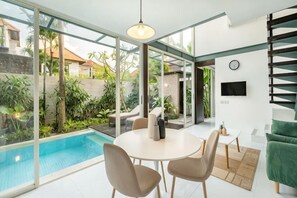 A modern interior with a pool, dining area, and outdoor view. - Villa De Luca By Aishwarya Bali International (Bali)