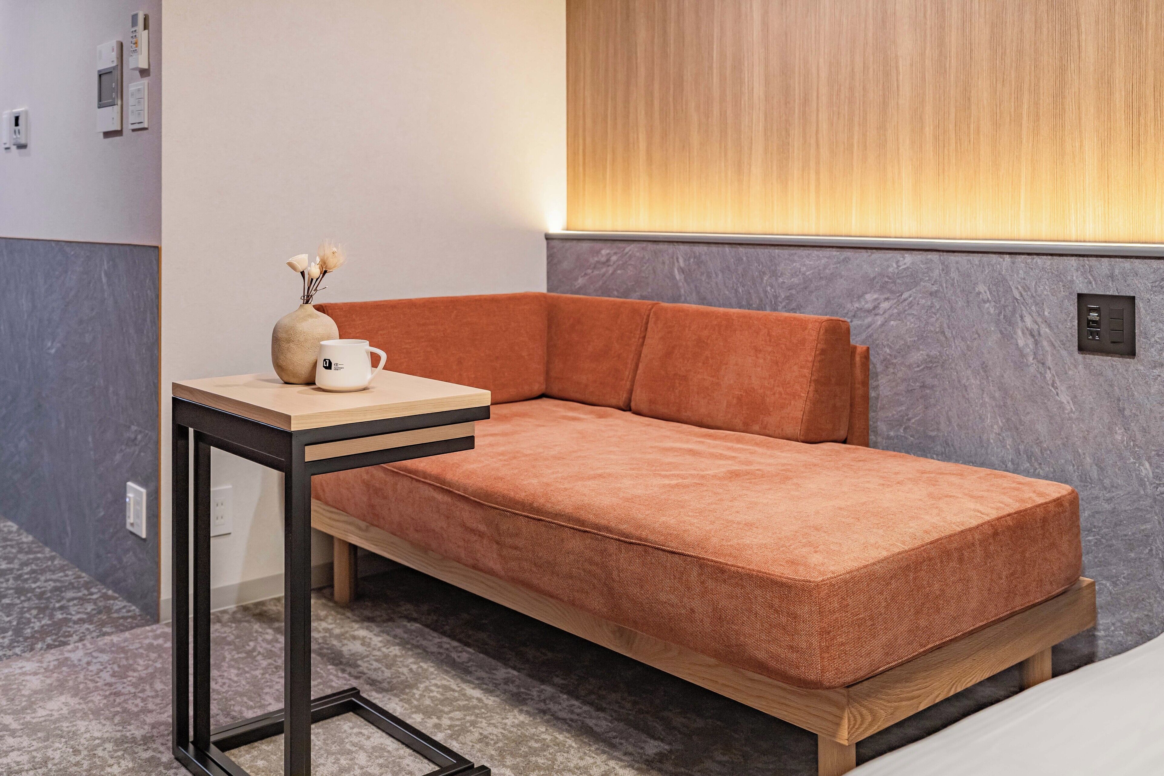 A modern room with a sofa, a small table, and a vase with flowers.