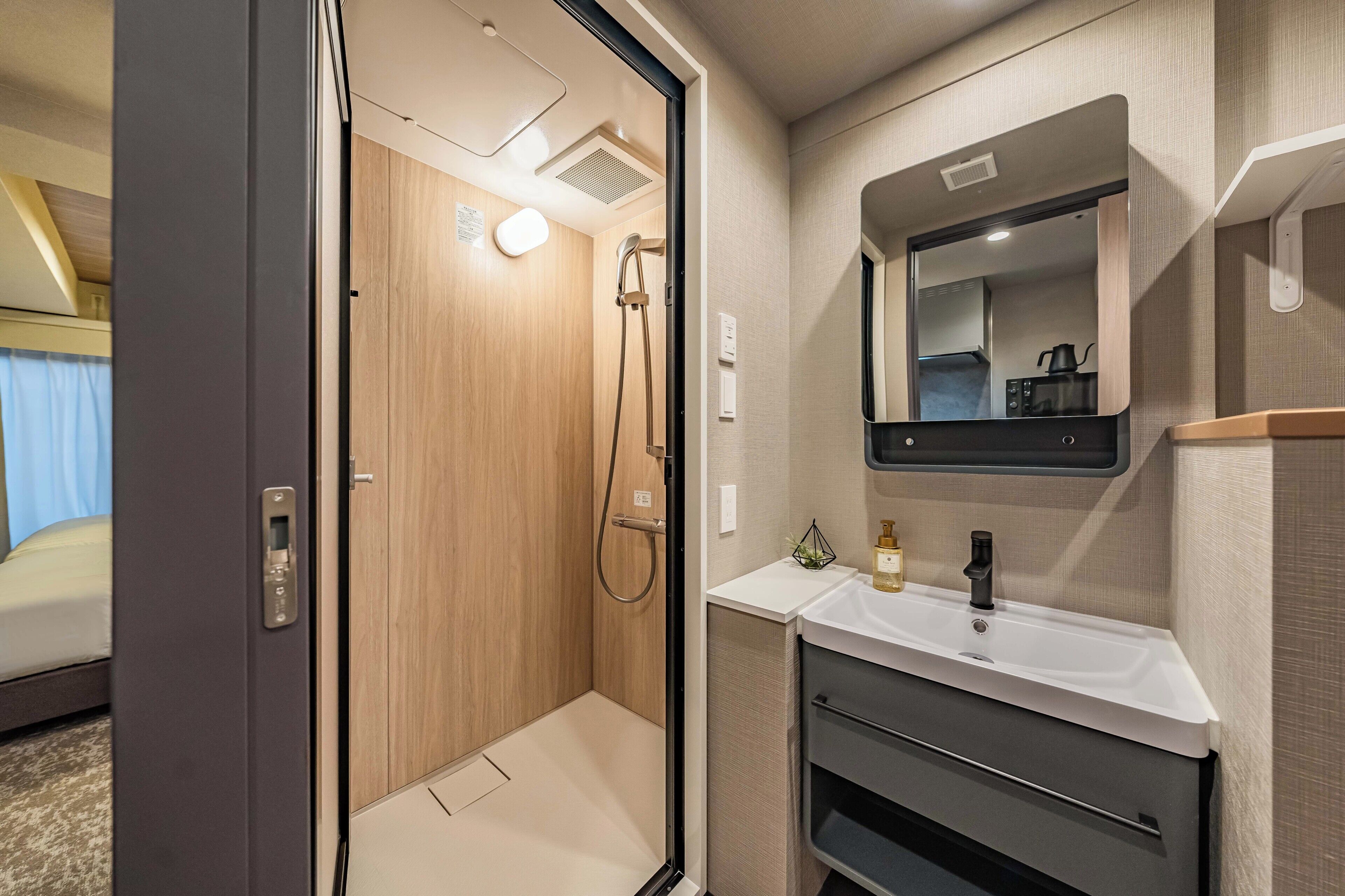 A compact bathroom with a shower, a sink, and a mirror.