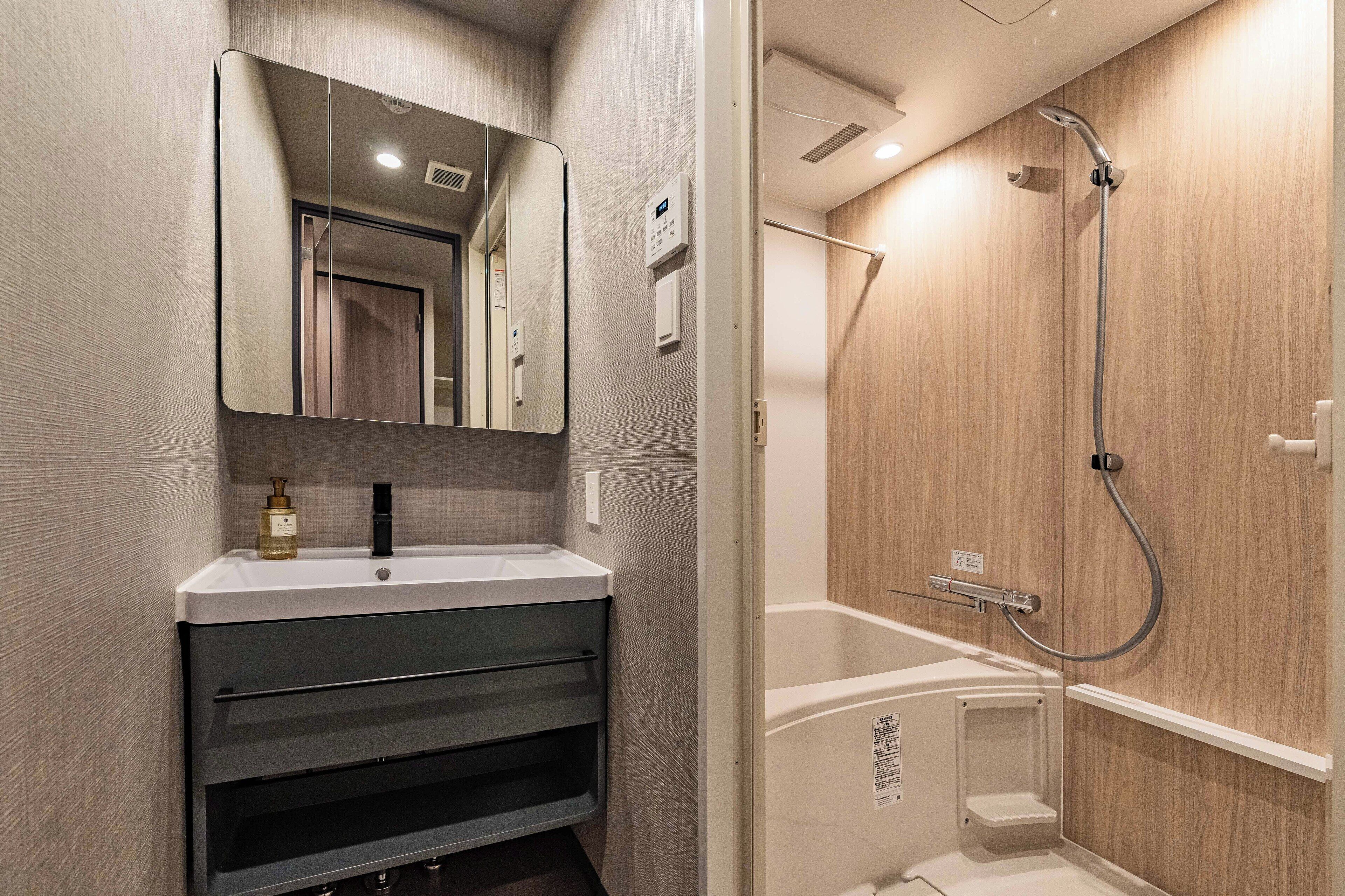 A modern bathroom with a vanity, mirror, and shower.