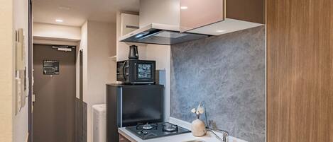 Une cuisine compacte équipée d’une cuisinière intégrée, d’une machine à café et d’un évier.