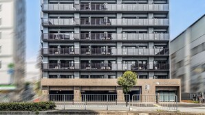 A multi-story building with a modern architectural design, featuring a series of balconies and a flat roof. - Apartment Hotel 11 Shinimamiya 3 (Osaka)