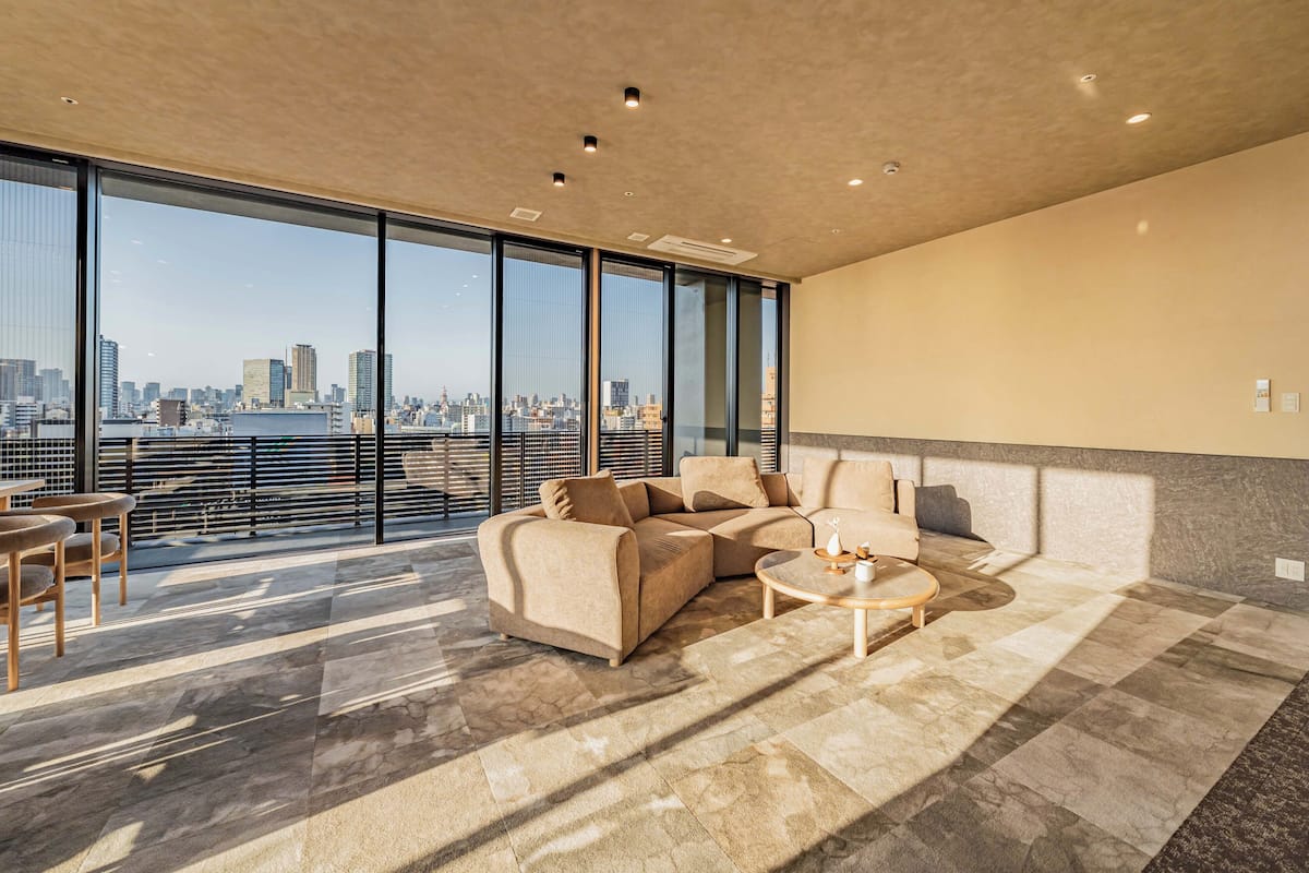 Amplia sala de estar con un gran ventanal, un sofá modular, una mesa de centro redonda y vistas a la ciudad.