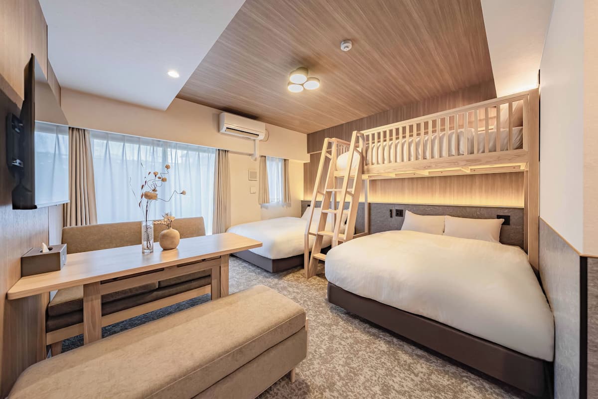 Una habitación de hotel moderna con literas, un escritorio, una silla y una mesita de noche.