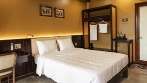 Ein Hotelzimmer mit Bett, Schreibtisch, Stuhl, Spiegel und Garderobe.